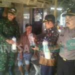 Petugas menunjukkan hasil tangkapan miras jenis arak dan toak. foto: GUNAWAN/ BANGSAONLINE