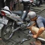 Seorang pedagang mengganti knalpot motor pelanggan di sebuah toko onderdil sepeda motor bekas. (ft: tempo)