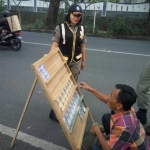 Salah satu petugas Banpol Satpol PP Kota Malang saat memberikan sosialisasi kepada penjual jasa penukaran uang agar tidak mangkal di tempat umum. foto: IWAN IRAWAN/ BANGSAONLINE