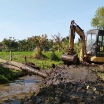 Alat berat sedang bekerja mengeruk sungai.