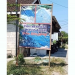 Banner bertuliskan wisata jalan berlubang di Desa Nguntoronadi, Magetan.