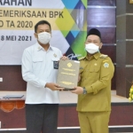 Bupati Gresik Fandi Akhmad Yani menerima buku laporan keuangan dari Kepala BPK Perwakilan Jawa Timur Joko Agus Setyono. foto: SYUHUD/ BANGSAONLINE