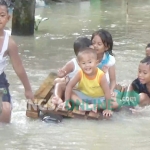 Para bocah tampak menikmati banjir untuk bermain air.