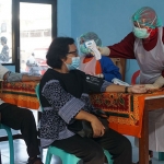 Petugas mengecek suhu tubuh lansia yang akan ikut vaksinasi di Kelurahan Burengan. (foto: ist)