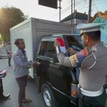 Anggota Satlantas Polres Tuban saat memasangkan bendera merah putih ke salah satu mobil pengangkut barang.
