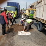 Polantas dan warga sedang melakukan perbaikan jalan provinsi di Kejapanan. SUPARDI/BANGSAONLINE