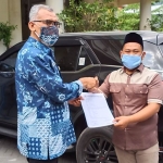 Ketua DPRD Gresik, Fandi Akhmad Yani saat mengembalikan mobdin tipe Toyota Fortuner kepada Sekwan DPRD Gresik, Darmawan. (foto: SYUHUD/ BANGSAONLINE)