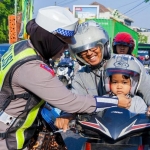 Salah satu Anggota satlantas Polres Pasuruan saat membagikan helm SNI. Foto: Andy Fachrudin