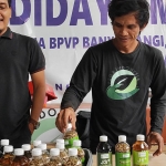 Ketua Pokmas Pega Indonesia Sundariyanto (kanan) menunjukkan produk maggot kering dan larutan jamur jakaba dari pengolahan sampah organik. Foto: BANGSAONLINE