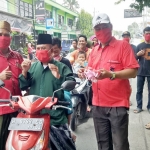 Sekretaris DPC PDIP Gresik Noto Utomo (kiri) ketika membagikan masker kepada pengguna jalan. foto: SYUHUD/ BANGSAONLINE