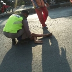 Bahrul Almi (12), saat ditolong oleh seorang polisi, usai terjatuh di jalan ketika hendak naik ke atas truk trailer.