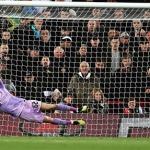 Kiper Liverpool Caoimhín Kelleher menepis tendangan pemain Derby County dalam adu penalti.