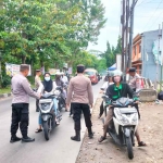 Petugas dari Polsek Sedati saat mengedukasi pengendara yang tidak memakai helm SNI saat melintas di Jalan Raya Pulungan.