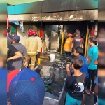 Petugas saat melakukan pendinginan pom mini di Waru, Sidoarjo, yang terbakar.