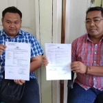 Riksa Firman Santoso didampingi kuasa hukumnya, Bahtiar Pradinata, menunjukkan bukti laporan dari Polrestabes Surabaya.