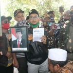 Ketua PC Ansor Bangil Saad Muafi menunjukkan foto Presiden RI Jokowi yang dicoret-coret dan berkas HTI saat mendatangi Abdul Halim di Bangil Pasuruan Jawa Timur, Sabtu (22/8/2020). foto: ahmad fuad/ bangsaonline.com