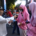 Ketua Tim Satlak P4GN Lamongan Kartika Hidayati saat membagikan bunga dan masker kepada warga.

