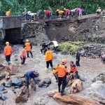Petugas BPBD Blitar dibantu warga saat melakukan pembersihan jembatan putus akibat banjir bandang di Dusun Barurejo, Desa Krisik, Kecamatan Gandusari.