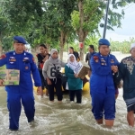 Dirpolairud Polda Jatim AKBP Puji Hendro Wibowo membantu warga menerobos jalan  yang terendam banjir. Foro: SYUHUD/ BANGSAONLINE