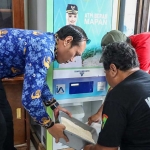 Kepala Dinsos Kota Kediri, Imam Muttaqin (kiri), saat membantu warga mengambil beras melalui ATM Beras. Foto: Ist