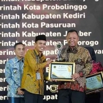 Pjs Bupati Kediri, Heru Wahono Santoso, saat menerima piagam penghargaan dari Ketua Informasi Publik Jatim, Edi Purwanto. Foto: Ist 