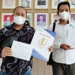 Sulton Sulaiman, S.H (kiri), Kuasa Hukum Pj. Kades Munggugianti menunjukkan bukti pelaporan di Mapolres Gresik. foto: SYUHUD/BANGSAONLINE