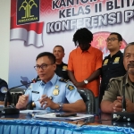 Kantor Imigrasi Kelas II Blitar saat menggelar konpers. Tampak Konan Nzue Ange Olivier (kemeja oranye) tertunduk pasrah saat diapit petugas. 