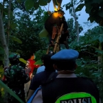 Petugas dibantu warga sedang mengevakuasi tubuh korban dari atas pohon.