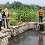 Edi Handoyo dan Peni Wulandari saat menunjukkan air untuk irigasi sawah yang berwarna keabu-abuan di saluran Dusun Pulorejo Desa Tengger Lor, Kecamatan Kunjang, Kabupaten Kediri, Kamis (29/4). foto: MUJI HARJITA/ BANGSAONLINE