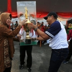 Camat Tambaksari, Ridwan Mubarun menyerahkan piala bergilir juara umum ke Wali Kota Risma.