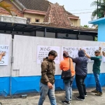 Massa Aksi saat memasang poster di pintu gerbang SPPG Bandar Lor. Foto: Muji Harjita/Bangsaonline.