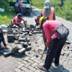 Petugas Bidang Bina Marga DPUTR Gresik saat memperbaiki jalan Mengare. Foto: SYUHUD/ BANGSAONLINE