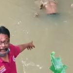 Seorang warga sedang menunjuk ke arah mayat yang terapung di sungai. 