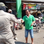 Petugas Satpol PP Kota Kediri saat memberikan masker kepada pengunjung pasar. (foto: ist.)