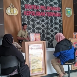 AA didampingi rekannya saat melaporkan sang suami ke Polres Madiun Kota. Foto: HENDRO SUHARTONO/ BANGSAONLINE