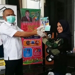 Anggota DPR RI H. Syafiuddin Asmoro saat menyerahkan masker dan hand sanitizer kepada salah satu relawan Song Osong Lombung.
