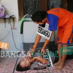 Tersangka saat memperagakan adegan mencekik korban. foto: AAN AMRULLOH/ BANGSAONLINE