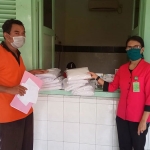 Petugas Pemkot sedang menyerahkan kain kafan dan kapas kepada pihak rumah sakit untuk perawatan jenazah Covid-19. (foto: ist).