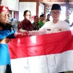 Bupati Pamekasan H. Baddrut Tamam saat secara simbolis menyerahkan bendera merah-putih kepada perwakilan warga. 