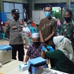 Petugas Polsek Manyar saat mengawal vaksinasi di Balai Desa Pongangan, Kecamatan Manyar. Foto: SYUHUD/BANGSAONLINE