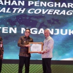 Pj Bupati Nganjuk saat menerima penghargaan UHC pada peringatan Hari Kesehatan Nasional ke-60.