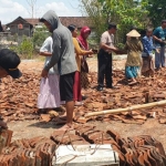 Polisi bersama masyarakat bergotong-royong membersihkan puing-puing reruntuhan rumah yang diterjang angin puting beliung. foto: BAMBANG/ BANGSAONLINE