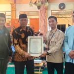 Kepala Cabang Yatim Mandiri Kota Batu, M. Haafidhuddin, saat menyerahkan piagam penghargaan ke Kepala SMAN 2 Batu, Wartono.