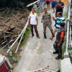 Anggota Koramil 0812/07 Bluluk saat meninjau kondisi jembatan penghubung Lamongan–Bojonegoro yang putus akibat banjir Sungai Semar Mendem, Jumat (21/11/2025). 