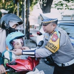 Kasatlantas Polres Gresik, AKP Rizki Julianda Putera Buna, ketika memberikan helm kepada salah satu pengendara. Foto: Ist