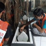 Para remaja yang terjaring razia sedang membersihkan makam Mbah Bungur.