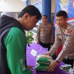 Wakapolres Gresik Kompol Danu Anindhito (kanan) melayani pembeli di gelaran pangan murah. Foto: Ist.
