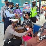Kasat Lantas Polres Pamekasan AKP Deddy Eka Priyanto saat memasangkan masker kepada anak kecil dan mengharapkan tetap mematuhi protokol kesehatan. (foto: ist)