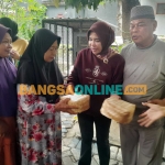 Wabup Mimik Idayana didampingi Rahmat Muhajirin membagikan paket daging kurban ke warga sekitar, Rabu (27/5/2026). foto: Mustain/BANGSAONLINE