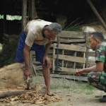 Kopda Simun saat melihat Raseno mengukir kayu gembol. foto: BAMBANG/ BANGSAONLINE